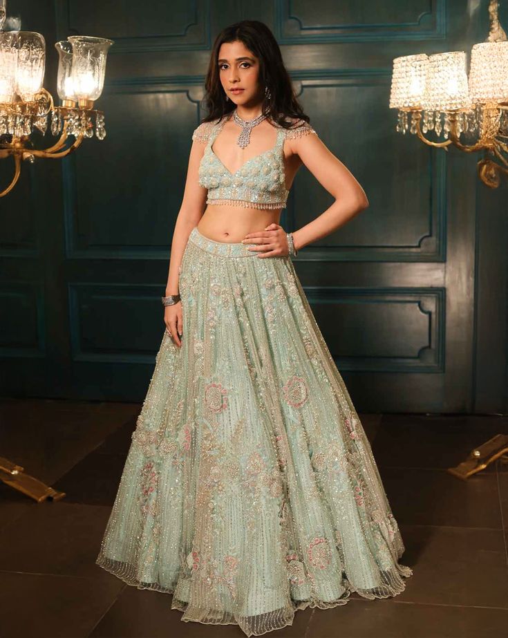 This sea green lehenga features hand embroidered 3D flowers throughout along with sequin,crystal, pearl and cutdana embroidery. It is paired with a matching V neck blouse with tassel and shoulder cap detailing, including an embroidered dupatta.From Isa by Dolly Wahal's Fiori collection.DELIVERY TIMEPlease allow 8-12 weeks for your outfit to arrive.FABRIC DETAILSNetProfessional cleaning only. Designer Pista Green Choli With Sequins, Designer Pista Green Sequined Choli, Pista Green Sequined Choli For Designer Wear, Pista Green Floor-length Dress With Sequins, Pista Green Floor-length Sequin Set, Pista Green Sequin Sets For Reception, Designer Embellished Green Lehenga, Pista Green Anarkali Dress With Sequins, Designer Pista Green Sequin Dress