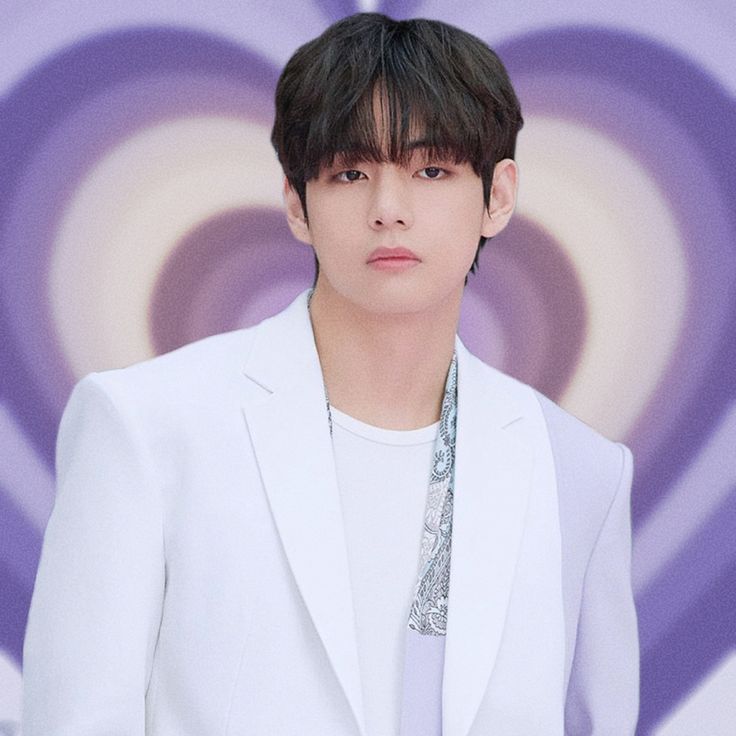 a young man in a white suit and tie standing next to a purple wall with circles on it