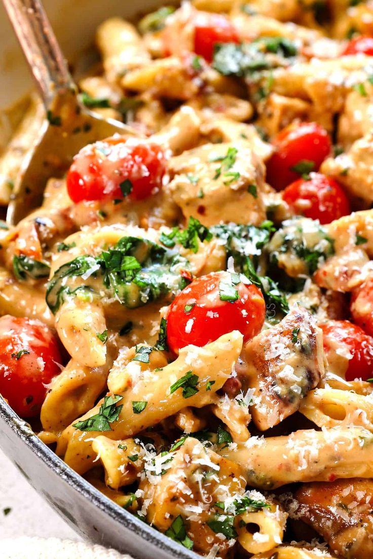 a pasta dish with tomatoes, chicken and spinach