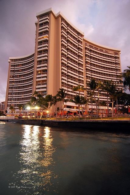 a large building sitting on the side of a body of water next to a beach