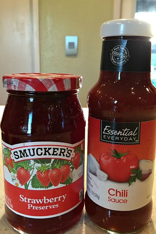 two jars of strawberry preserves sit on a counter top next to each other, one with an apple in it