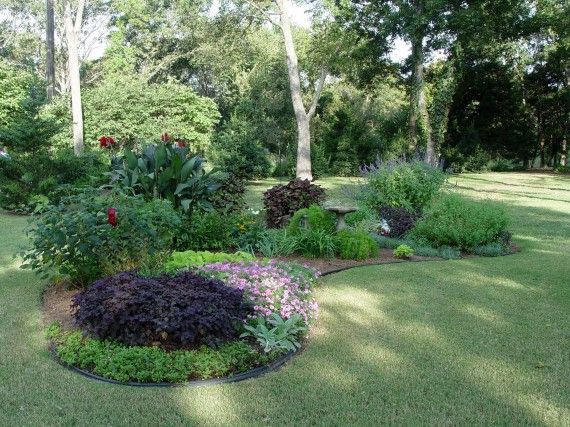 a garden with various plants and flowers in the center, surrounded by green lawning