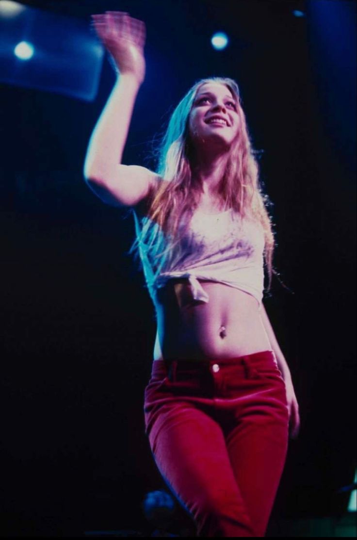 a woman is dancing on stage with her arms in the air