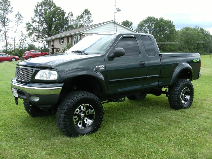 a large green truck parked on top of a lush green field