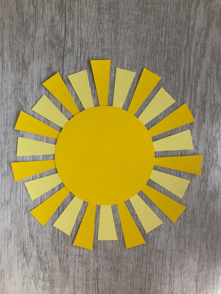 a yellow paper sun cut out on top of a wooden table