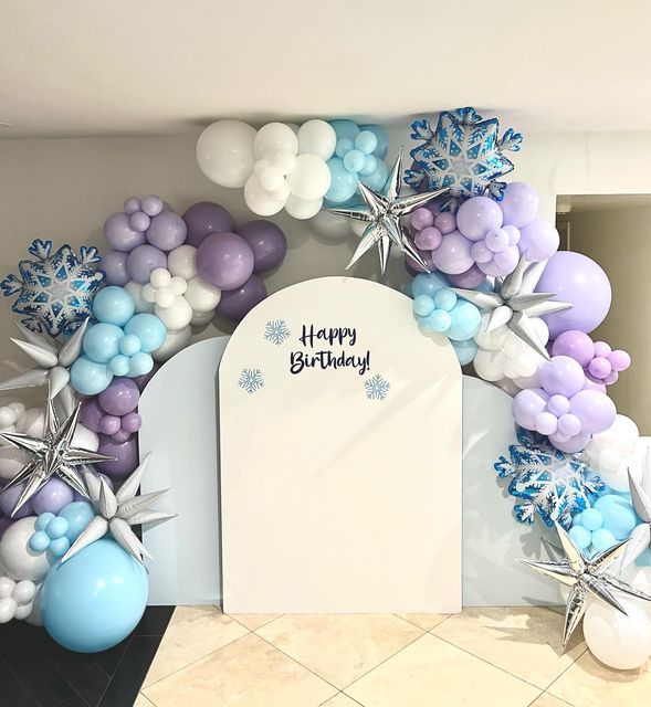 a birthday arch with balloons and snowflakes on it in the shape of stars