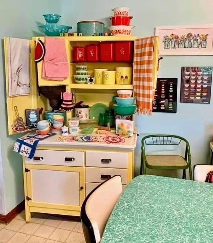 an old fashioned kitchen with yellow cabinets and green tablecloth