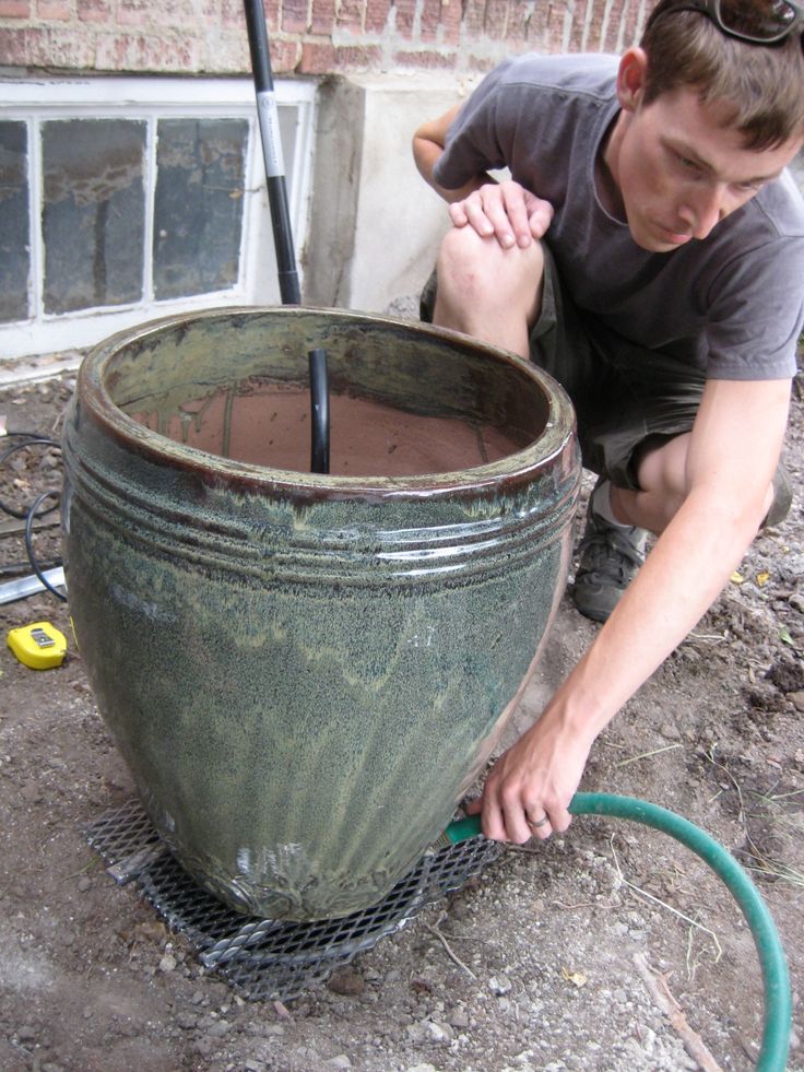 a man working on a large pot with a hose attached to the side of it