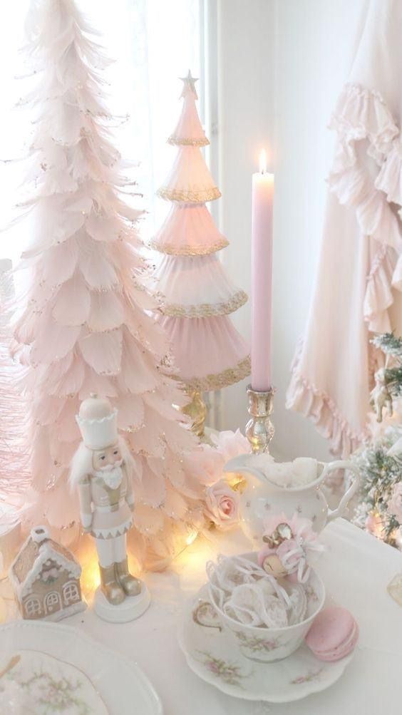 a white table topped with lots of pink christmas trees next to candles and dishes on top of it