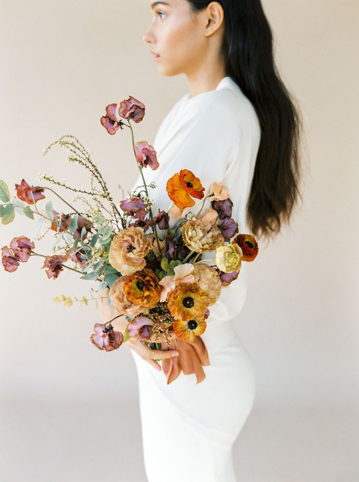 a woman holding a bouquet of flowers in her hands