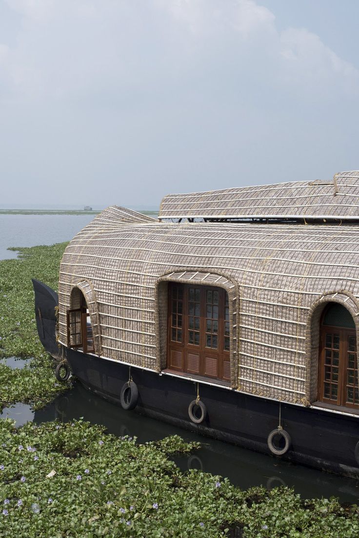 a house boat is floating in the water with green plants around it's sides