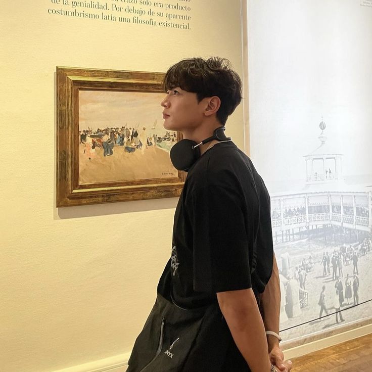 a young man standing in front of a painting