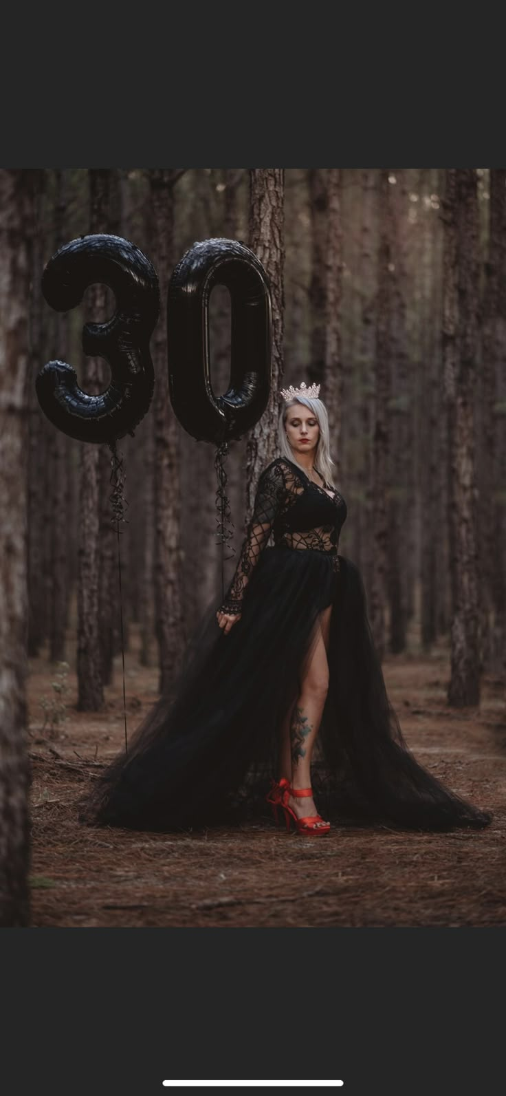 a woman in a black dress and crown standing next to a tree with the number 30 on it