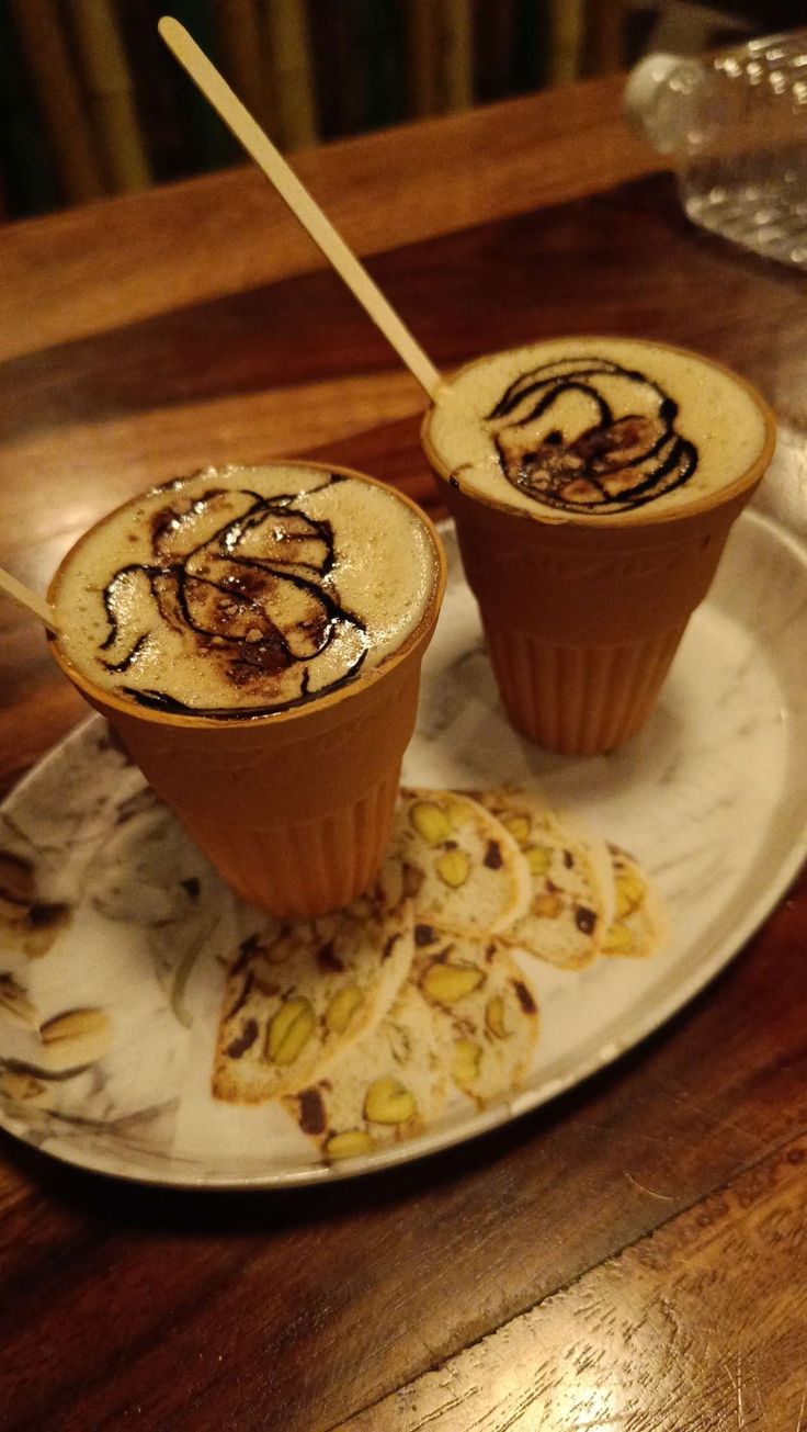 two cups filled with liquid sitting on top of a white plate