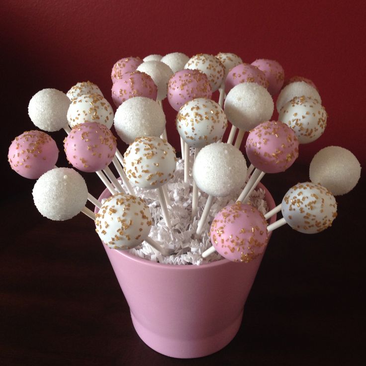 a pink cup filled with cake pops covered in white and gold sprinkles