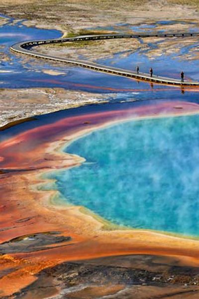 an aerial view of the grand prism in yellowstone national park with people walking over it