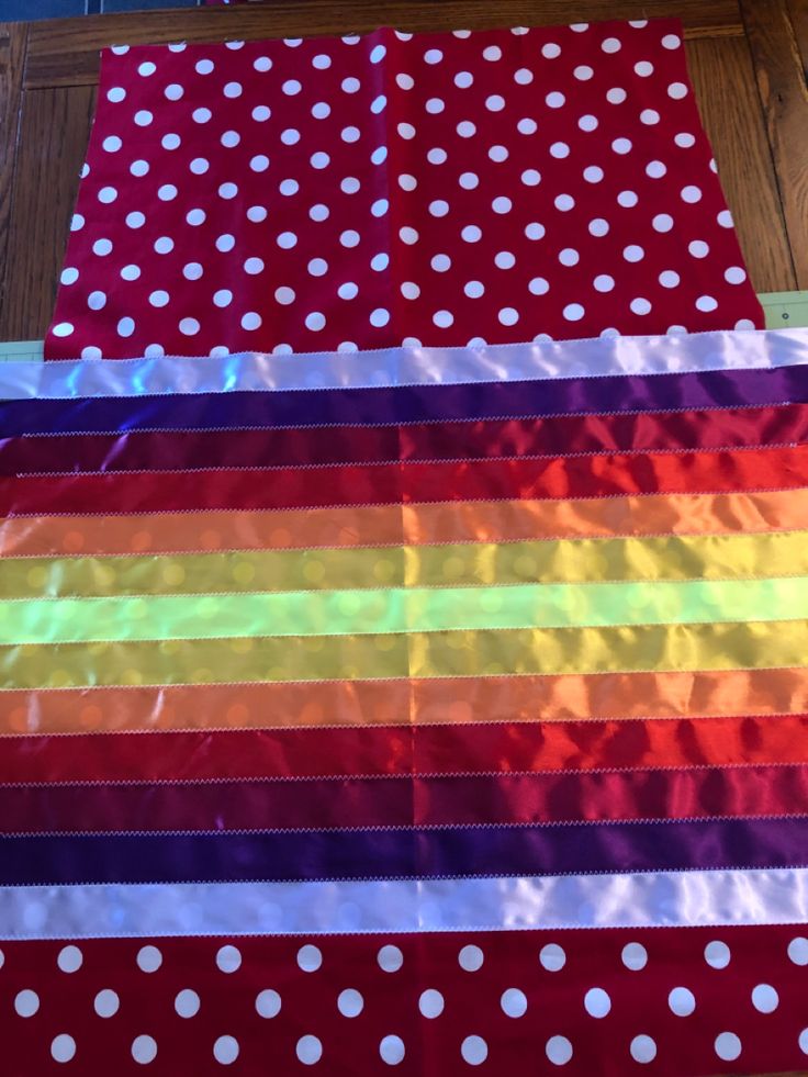 several different colors of fabric laid out on the floor with polka dots and rainbows