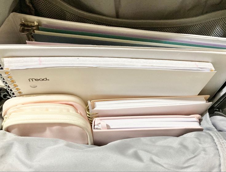 an open laptop computer sitting on top of a bag filled with files and folders