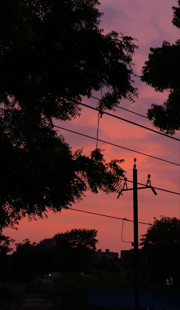 the sun is setting behind some power lines