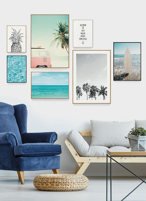 a living room with blue chairs and pictures on the wall above it, along with a wicker coffee table