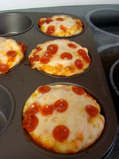 four mini pizzas in a muffin tin on the stove