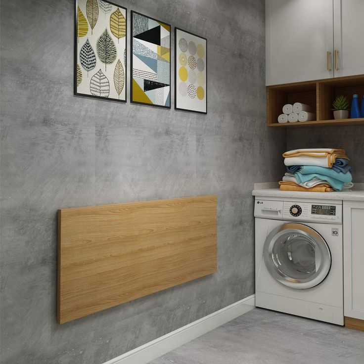 a washer sitting next to a dryer in a room with two pictures on the wall