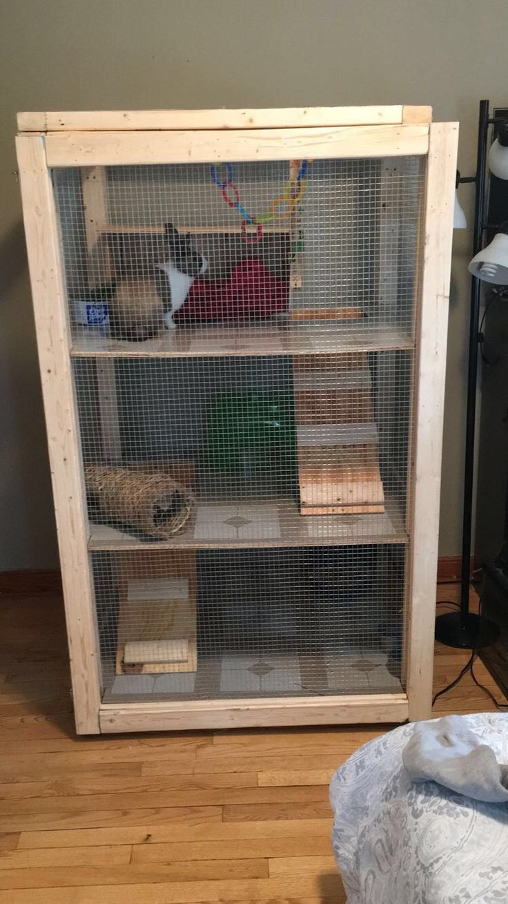 a caged shelf with books and other items in it on the floor next to a bed