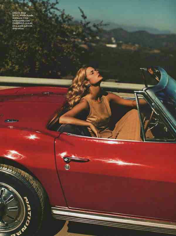 a woman sitting in the driver's seat of a red car