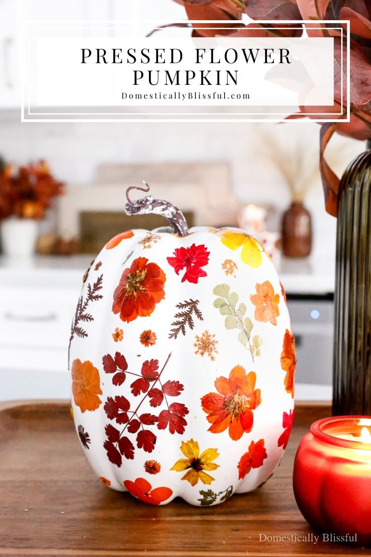 a white pumpkin sitting on top of a wooden table next to a vase filled with flowers