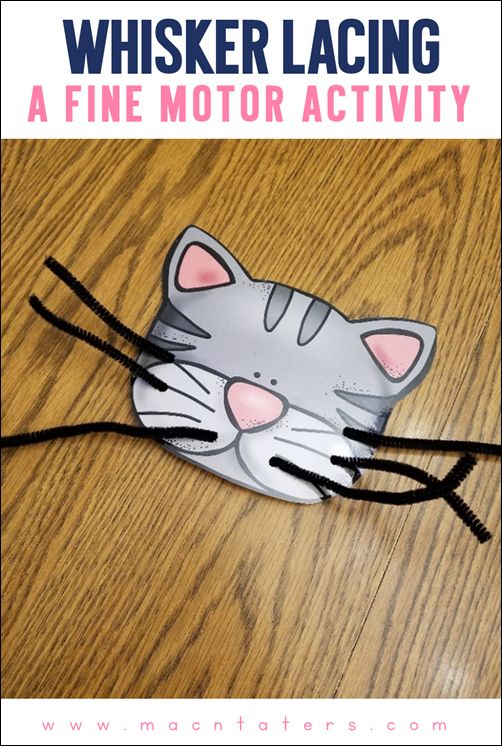 a paper cat mask with black string on the bottom and pink eyes sitting on a wooden table