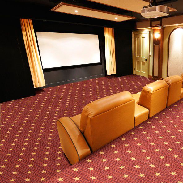 an empty theater room with two recliners and a projector screen