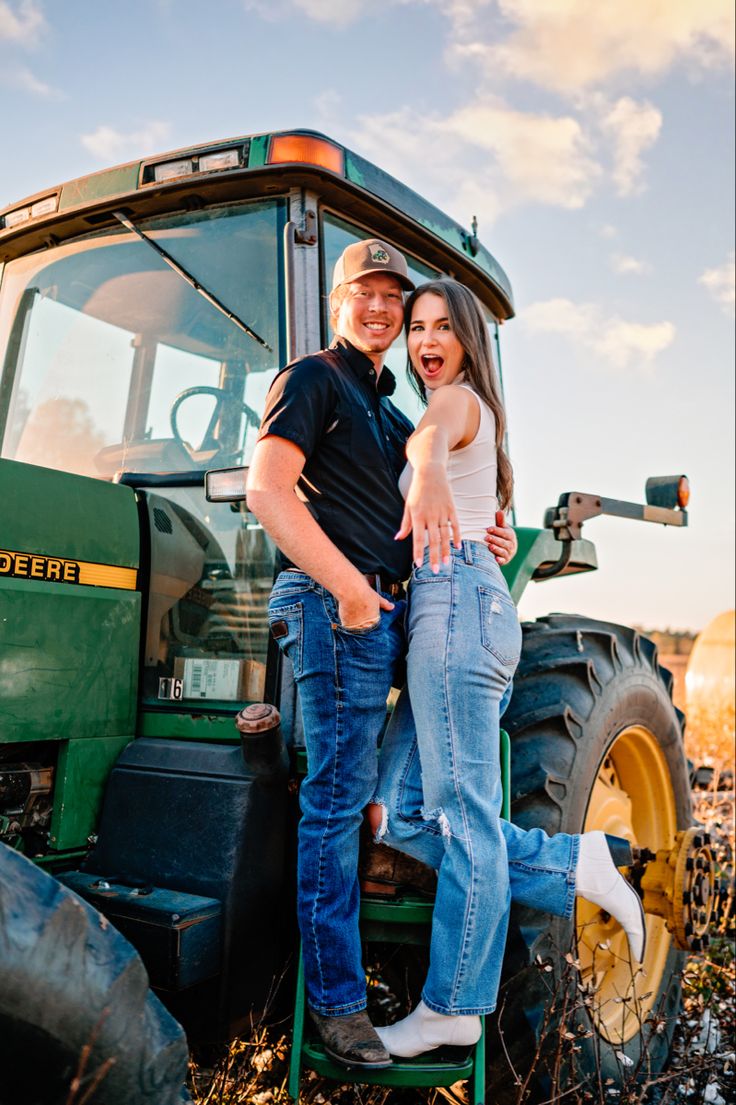 a man and woman standing in front of a tractor with the driver leaning on it