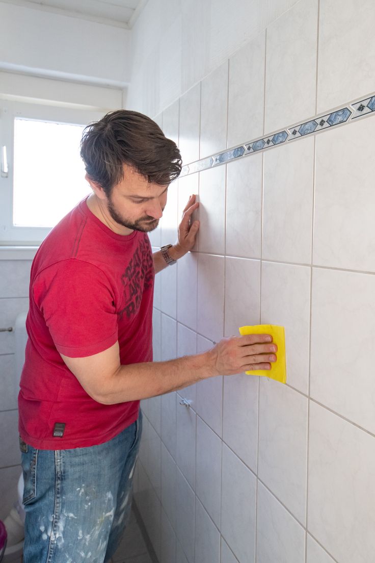 a man is cleaning the wall with a sponge