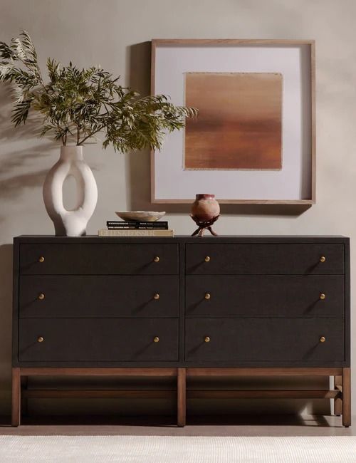 a black dresser with two vases and a painting on the wall