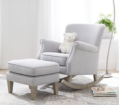 a white teddy bear sitting in a gray rocking chair with a footstool next to it