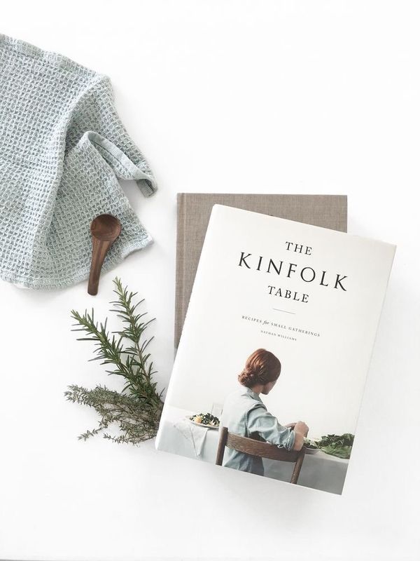 the kinfolk table book is sitting next to a pair of gloves and a plant