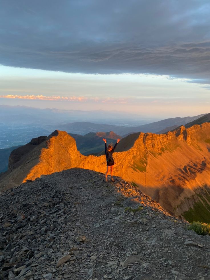 a person standing on top of a mountain with their arms in the air