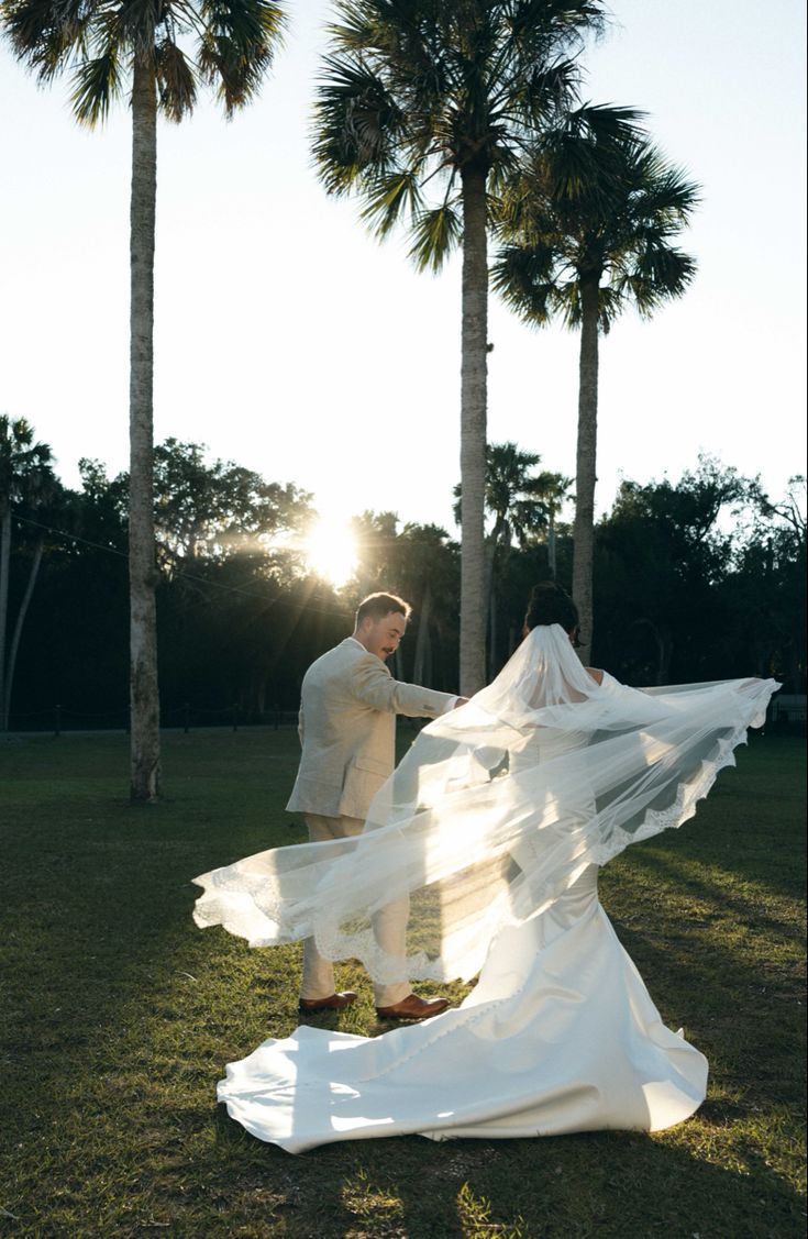 a bride and groom standing in front of palm trees