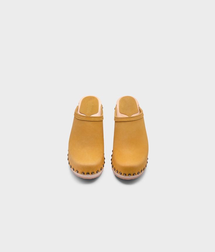 Made by skilled artisans in Sweden, these royal yellow nubuck clog mules feature a high heel and eye-catching stud detailing on the sides. From date nights to ladies' nights out, Rome delivers unparalleled style and confidence. Clog measurements:Heel height: 2 5/8” (6.5 cm)Toe height:﻿ 1 1/2″ (3.8 cm) Fit:NarrowLeather:Nubuck leatherClogs consist of:Base: European Lime Wood Sole: Rubber sole Fastening: Brass studs Clog Mules, Studded Clogs, Royal Yellow, Cork Sandals, Wooden Clogs, Clog Sandals, Date Nights, Ladies Night, Boot Shop