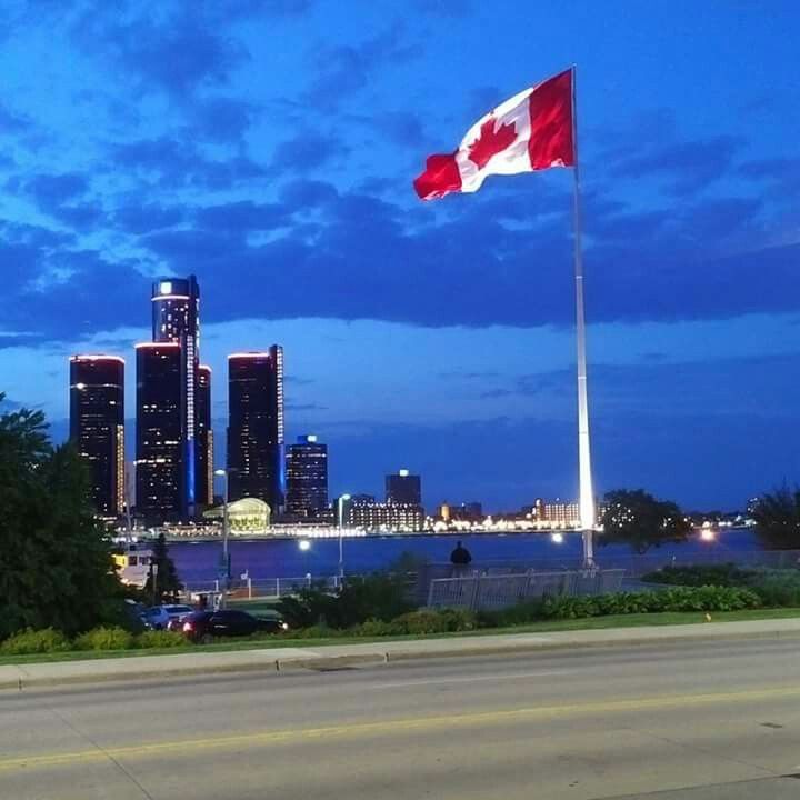 the canadian flag is flying high in the sky over the city skyline at night time