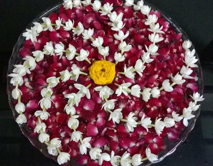 a bowl filled with red and white flowers on top of a black countertop next to a yellow button