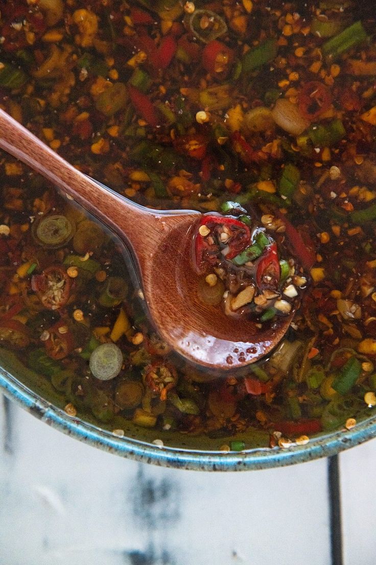 a wooden spoon filled with soup on top of a table