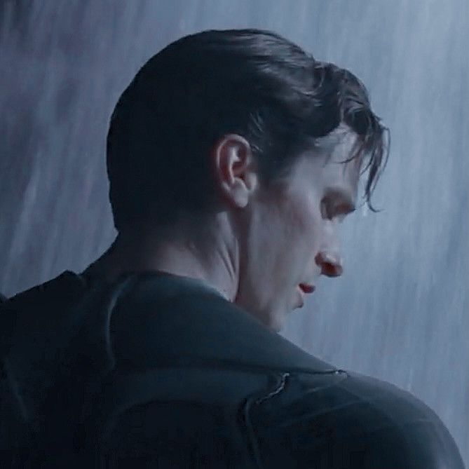 a man standing in the rain with his head turned to the side and eyes closed