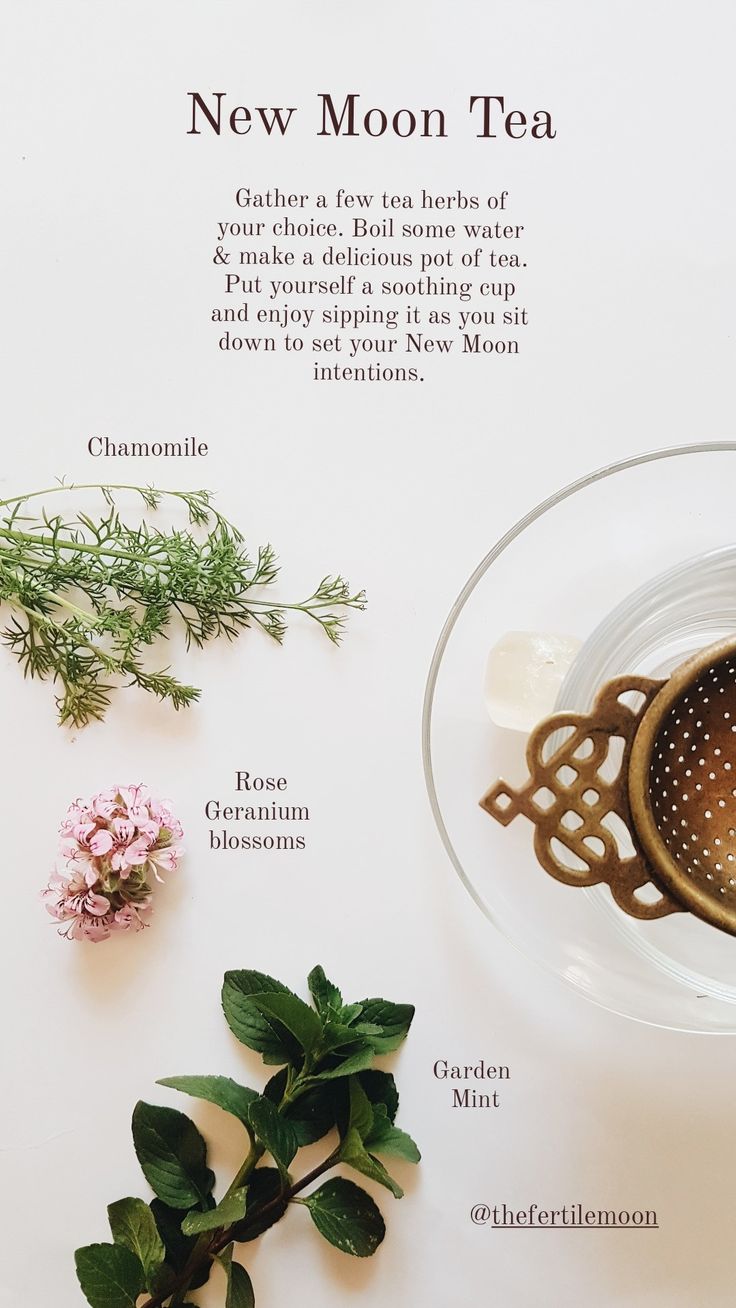 a cup of tea next to some flowers on a white surface with the words new moon tea