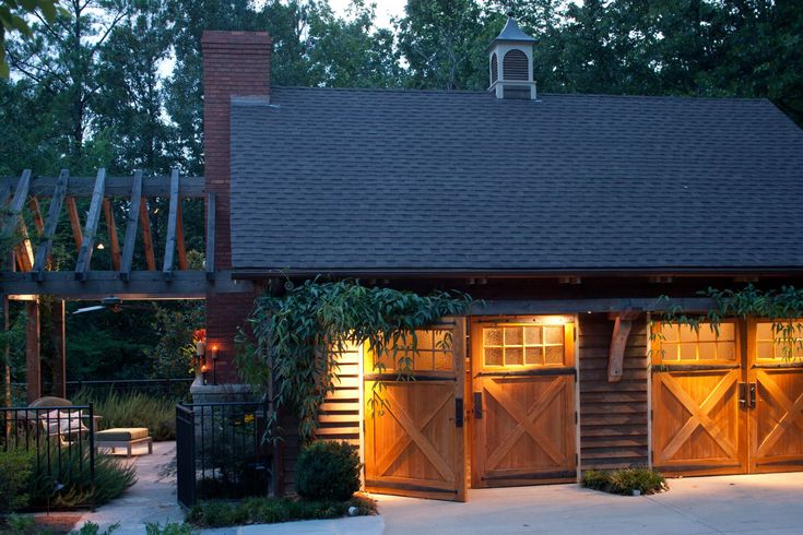 a small wooden building with two garage doors and lights on the side of it at night