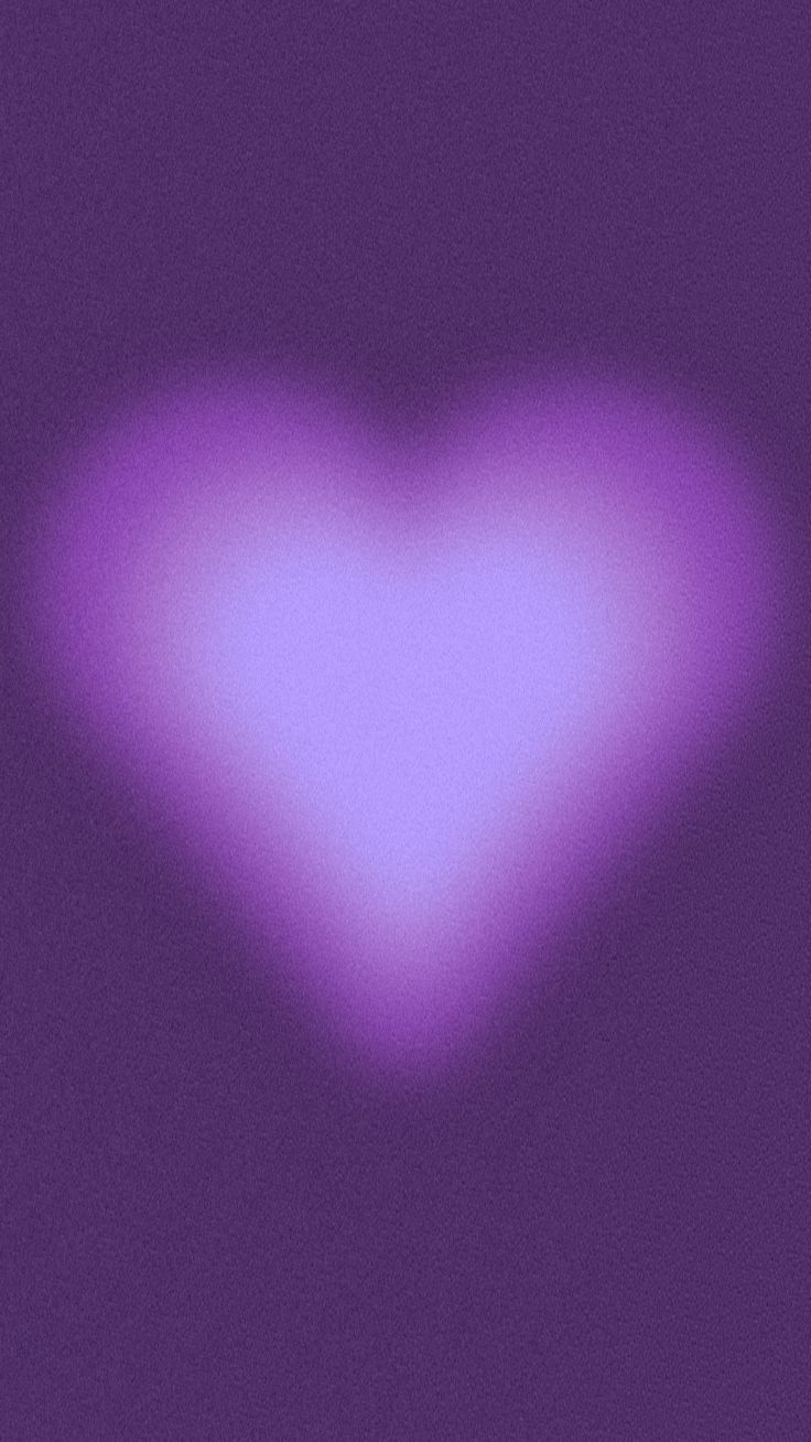 a blurry image of a heart shaped object on a purple background with the light reflecting off it's side