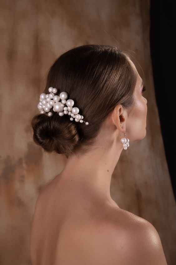 a woman in a wedding dress with pearls on her head and hair comb, looking off to the side