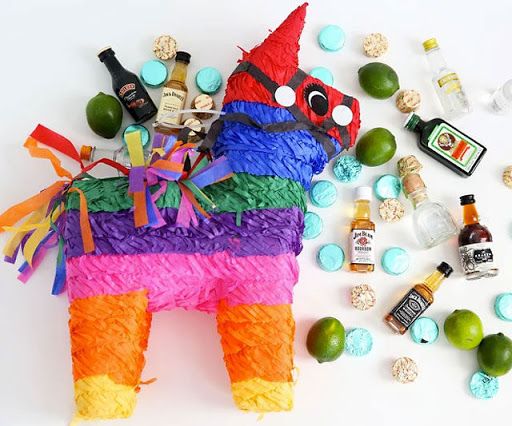 an animal made out of tissue paper surrounded by liquor bottles and candies on a white surface