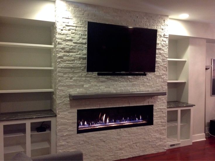 a white brick fireplace with a flat screen tv mounted on it's wall and built - in shelving