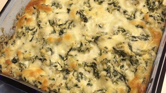 a casserole dish with spinach and cheese in it sitting on a table